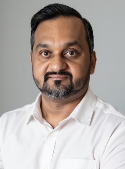 Raj in a white shirt against a plain grey studio backdrop
